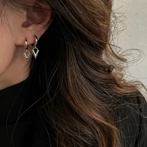 Detalle de pendiente de aro plateado con colgante en forma de V en modelo femenina