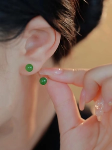 Primer plano de pendientes redondos de jade Hetian verde usados por una modelo