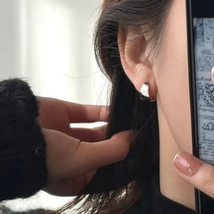 Pendientes de aro anchos en plata pulida con acabado de espejo usados por una modelo