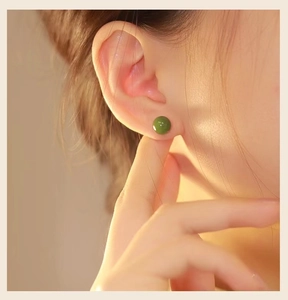 Detalle de pendiente de botón redondo en jade verde con textura brillante pulida