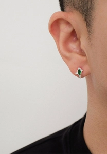 Primer plano de un pendiente de estrella plateado con circón verde en la oreja