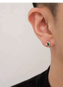 Primer plano de un pendiente de estrella para hombre con circonita verde en la oreja