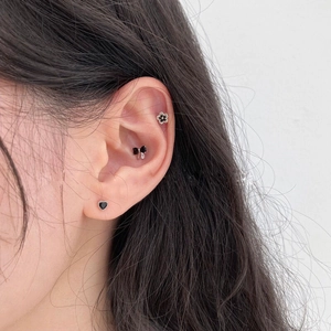Set di tre orecchini a perno con zircone nero, cuore, fiocco e fiore su modella
