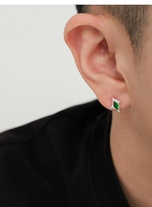 Primer plano de un pendiente de estrella plateado con piedra verde marquesa para hombre