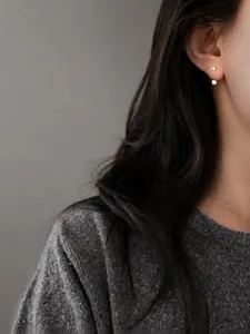 Detalle de elegantes pendientes de plata y circón usados con un suéter de punto gris