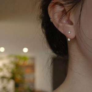 Pendientes minimalistas de plata con circonitas redondas en una modelo femenina