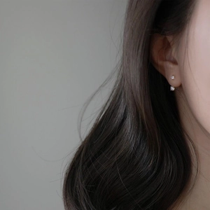 Pendientes de botón minimalistas con doble circón en plata S925 en una oreja mujer