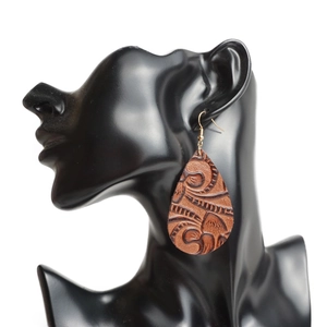 Boucles d'oreilles pendantes en cuir gaufré marron sur un présentoir de mannequin