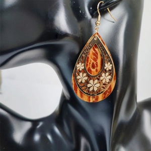 Detail of drop-shaped leather earrings with hollow gold flower overlay on black bust