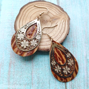 Detailed view of bohemian teardrop earrings with gold flower filigree and leather texture
