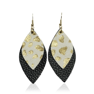 Macro detail of double-layered leaf earrings with gold speckled beige and black leather