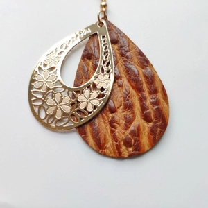 Detail of vintage teardrop earrings featuring golden cutout floral metal and brown leather