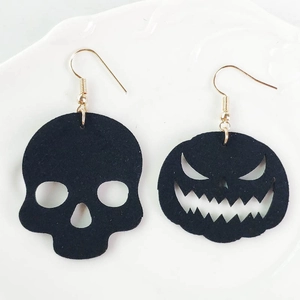 Detalle de pendientes asimétricos de Halloween con colgantes negros de calavera y calabaza