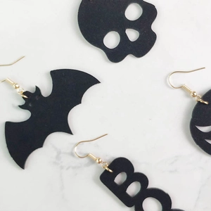 Set de pendientes de Halloween con murciélagos, calaveras y letras BOO sobre fondo de mármol