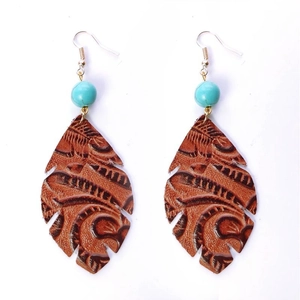 Détails macro de boucles d'oreilles en cuir en forme de feuille avec relief floral
