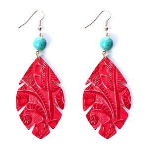 Gros plan sur les boucles d'oreilles en cuir rouge gaufré avec perle de turquoise