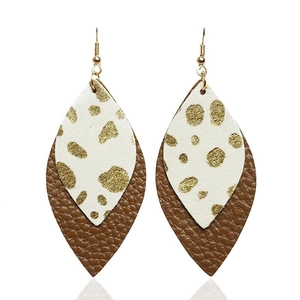 Macro detail of bohemian layered leather leaf earrings with gold speckled texture