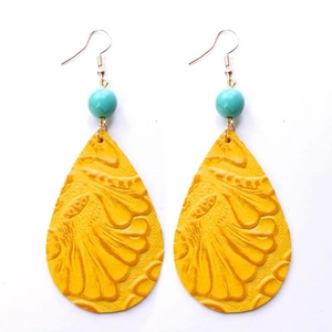 Détail de boucles d'oreilles en cuir jaune gaufré avec perles de turquoise bleues