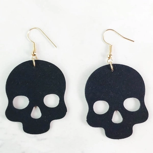 Detalle de pendientes góticos de calavera en cuero negro con ganchos de metal dorado