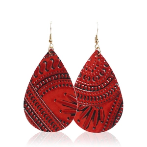 Détail macro de boucles d'oreilles en cuir rouge gaufré avec motifs floraux géométriques