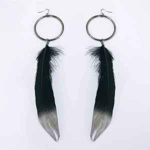 Detail of long black feather earrings with silver glitter gradient and metal hooks