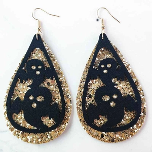 Detalle de pendientes fantasma de Halloween con recortes negros y purpurina dorada brillante