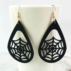 Detailed view of black laser-cut spider web teardrop earrings with gold hooks