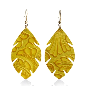 Vue détaillée des boucles d'oreilles en cuir jaune en forme de feuille avec motifs floraux