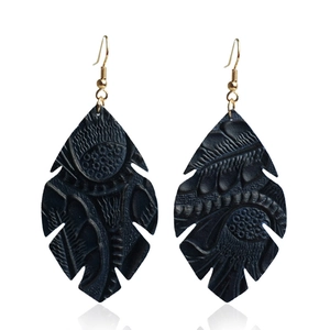 Vue détaillée des boucles d'oreilles en cuir en forme de feuille avec gaufrage sombre