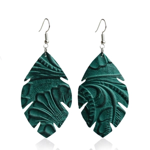Gros plan détaillé de boucles d'oreilles en cuir turquoise en forme de feuille ciselée