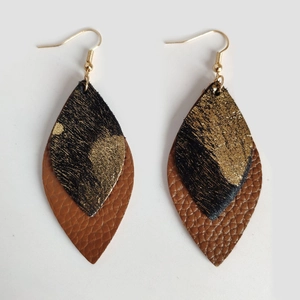 Detail of bohemian leaf earrings with gold foil and brown faux leather texture