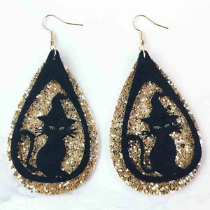 Detalle de pendientes de Halloween con purpurina dorada y diseño de gato negro y bruja