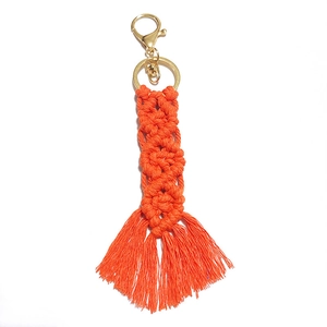 Handmade bohemian bright orange woven tassel keychain with golden metal clasp on white background