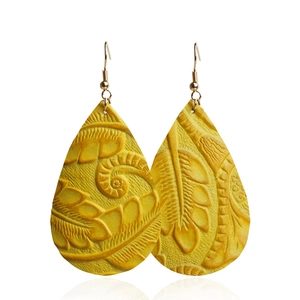 Gros plan de boucles d'oreilles gouttes en cuir jaune avec texture de feuille ciselée
