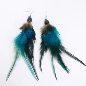 Close-up of bohemian peacock blue and black layered feather earrings with wooden beads