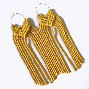 Detail of yellow macrame tassel earrings with golden circular loops in bohemian style