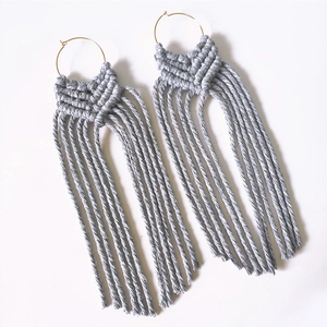 Handmade light grey macrame fringe earrings with gold metal hoops on white background