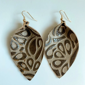 Détail des boucles d'oreilles en cuir en forme de feuille avec relief marron et crochets