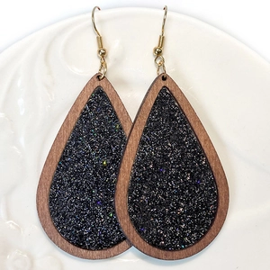 Traanvormige houten oorbellen met zwarte glitterinleg en goudkleurige haakjes