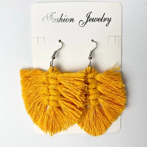 Close-up of bright yellow macrame fringe earrings with leaf-shaped woven texture