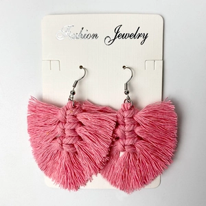 Detailed view of pink handmade woven tassel earrings with fan shape on white card