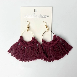Macro detail of bohemian wine red handmade cotton tassel fan earrings with gold rings