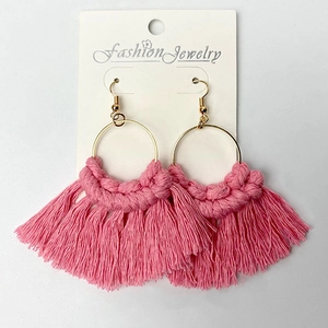 Detailed macro view of handmade pink cotton tassel earrings with gold metal rings