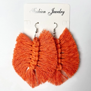 Detail of bright orange bohemian tassel earrings with handmade woven leaf texture