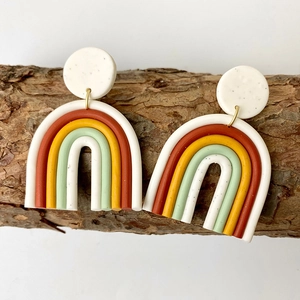 Dettaglio di orecchini arcobaleno in argilla a forma di U su sfondo in legno naturale