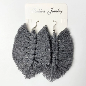 Detailed view of handmade grey cotton leaf fringe earrings on a white jewelry display card