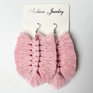 Close-up of handmade pink macrame leaf earrings with fringe on white jewelry card