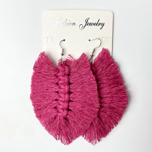 Detail of handmade rose pink woven tassel earrings with fringe on a display card