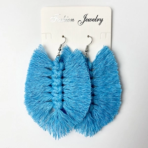 Close-up of light blue handmade woven fringe earrings with silver hooks on jewelry card