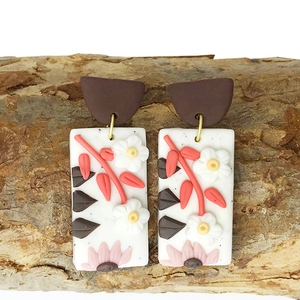 Handmade polymer clay earrings with floral relief on bark wood background
